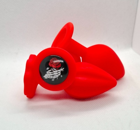 Czerwony korek analny „Red Rose” – silikonowy butt plug z ozdobną grafiką szkieletu dłoni trzymającej czerwoną różę.